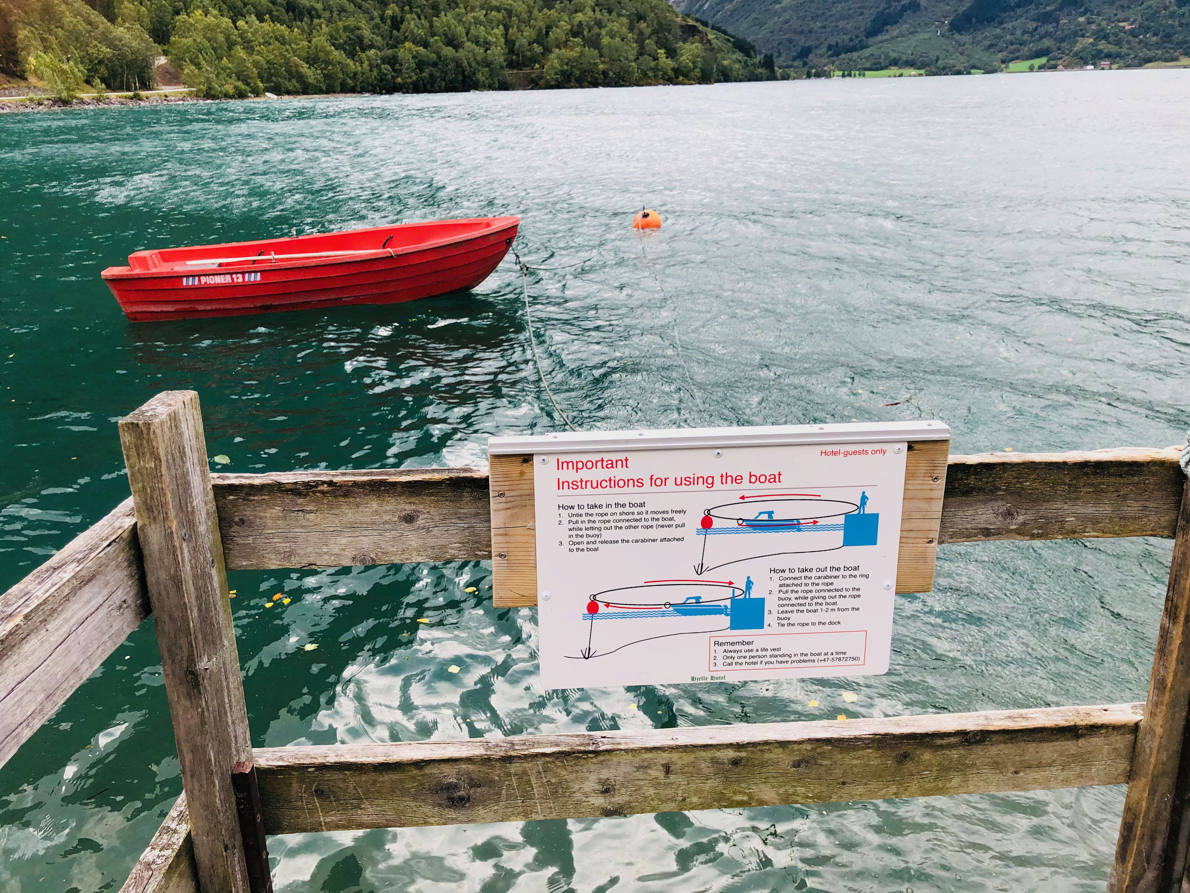A wooden dock with a signboard detailing instructions for using a red boat.