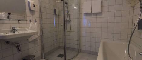 Un baño moderno con ducha de vidrio, lavamanos y bañera.