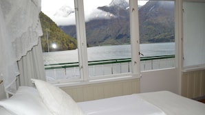 A bedroom with a bed, a window with a view of a lake and mountains. - Hjelle Hotel (Stryn)