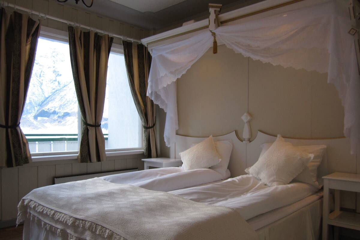 Un dormitorio con una cama doble, una mesita de noche y una ventana con cortinas.