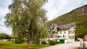 A large, multi-story building with a green and white facade, a balcony, and a green garage door. - Hjelle Hotel (Stryn)