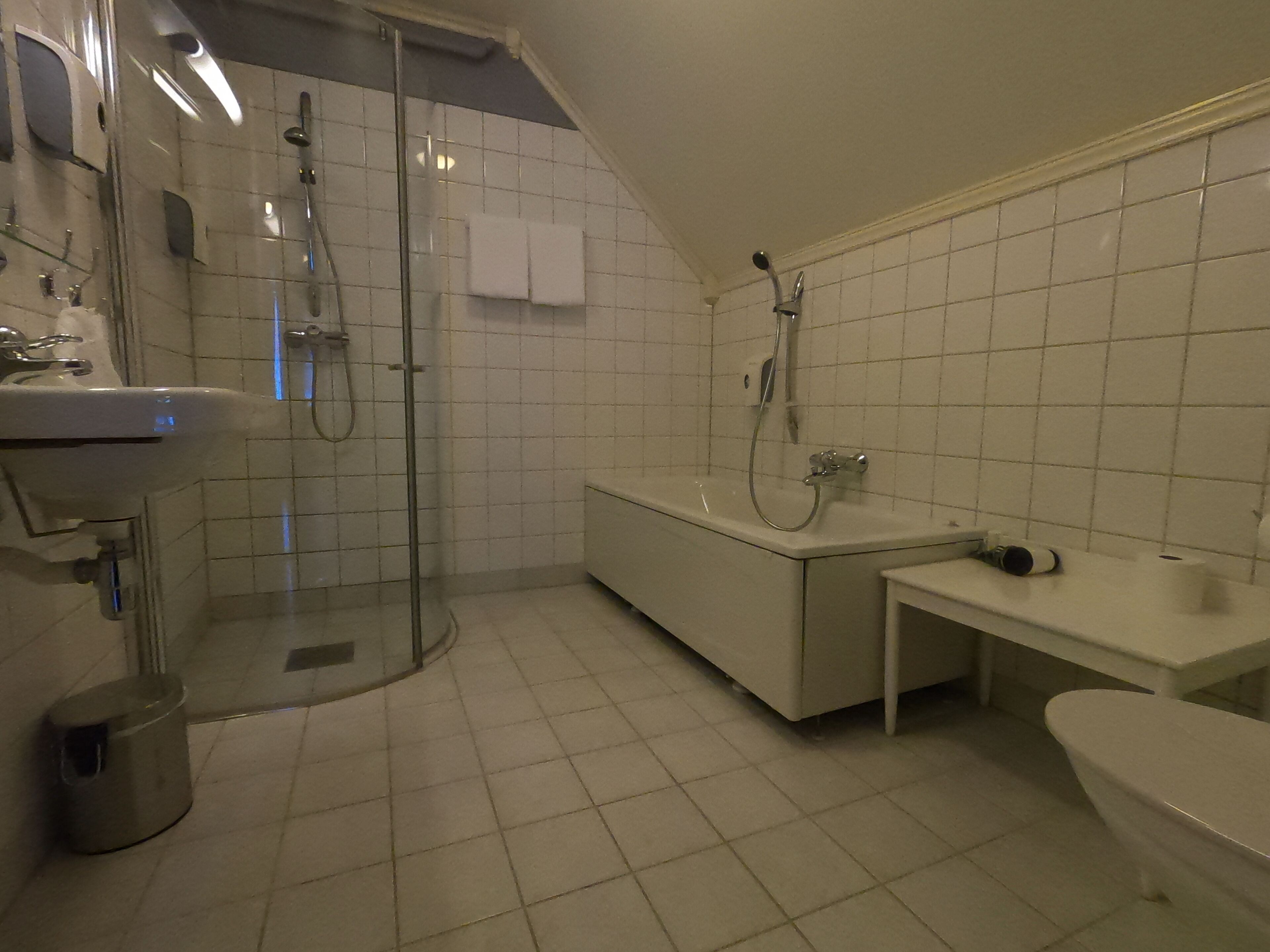 Un baño moderno con ducha de vidrio, bañera independiente, tocador con lavamanos y retrete.