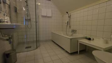Un baño moderno con ducha de vidrio, bañera independiente, tocador con lavamanos y retrete.