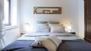 A neatly arranged bedroom with a large bed, two bedside tables with lamps, a mirror above the bed, and a window with curtains. - Lisetta Holiday homes - Ladybug House - Family House (Perugia)