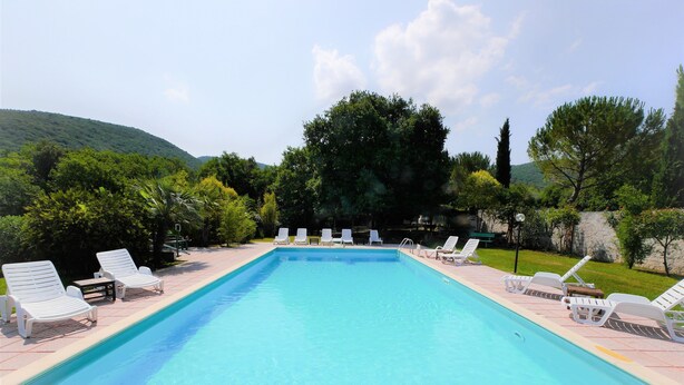 A rectangular swimming pool with clear blue water, surrounded by white lounge chairs and a paved deck. - Lisetta Holiday homes - Ladybug House - Family House (Perugia)
