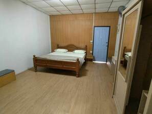 Un dormitorio con una cama de madera, una puerta azul y un armario.