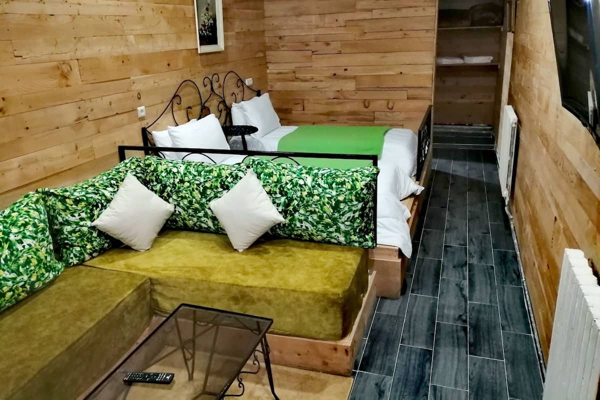 A compact room with a bed, a sofa, and a small table.