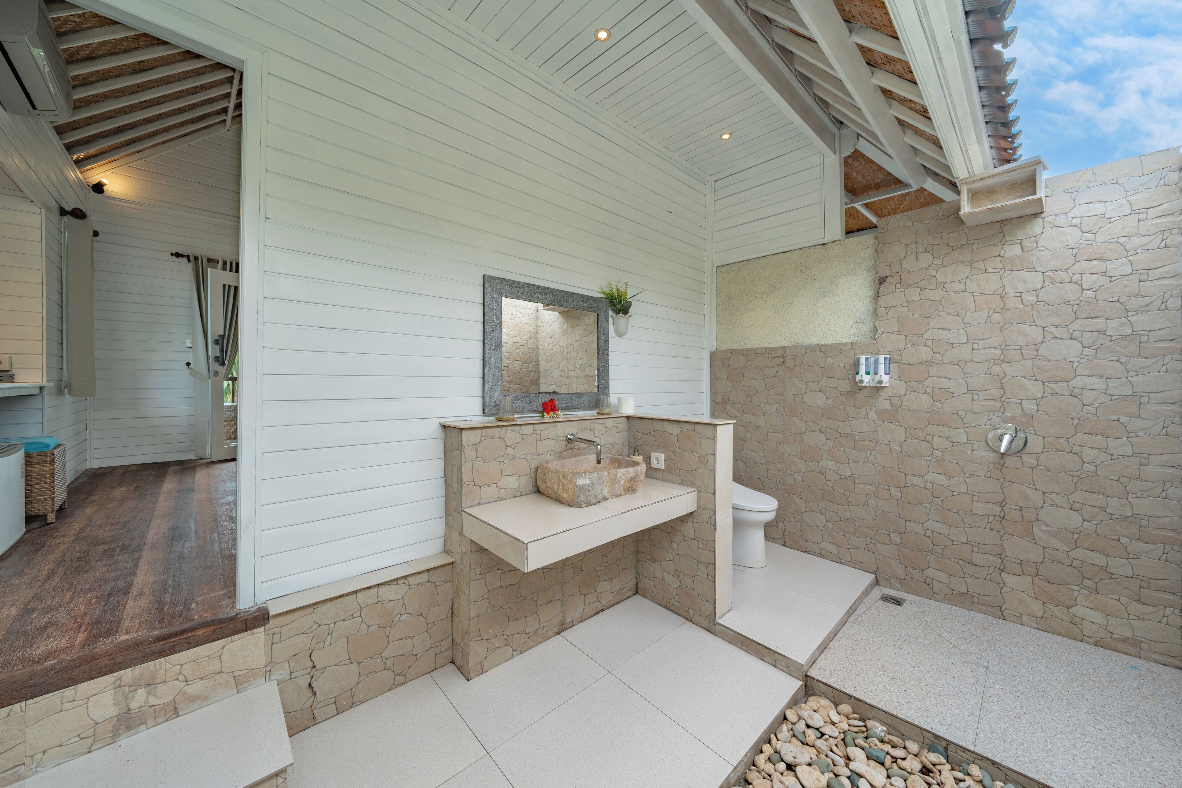 Een badkamer met een stenen muur, een wastafel met spiegel en een toilet.