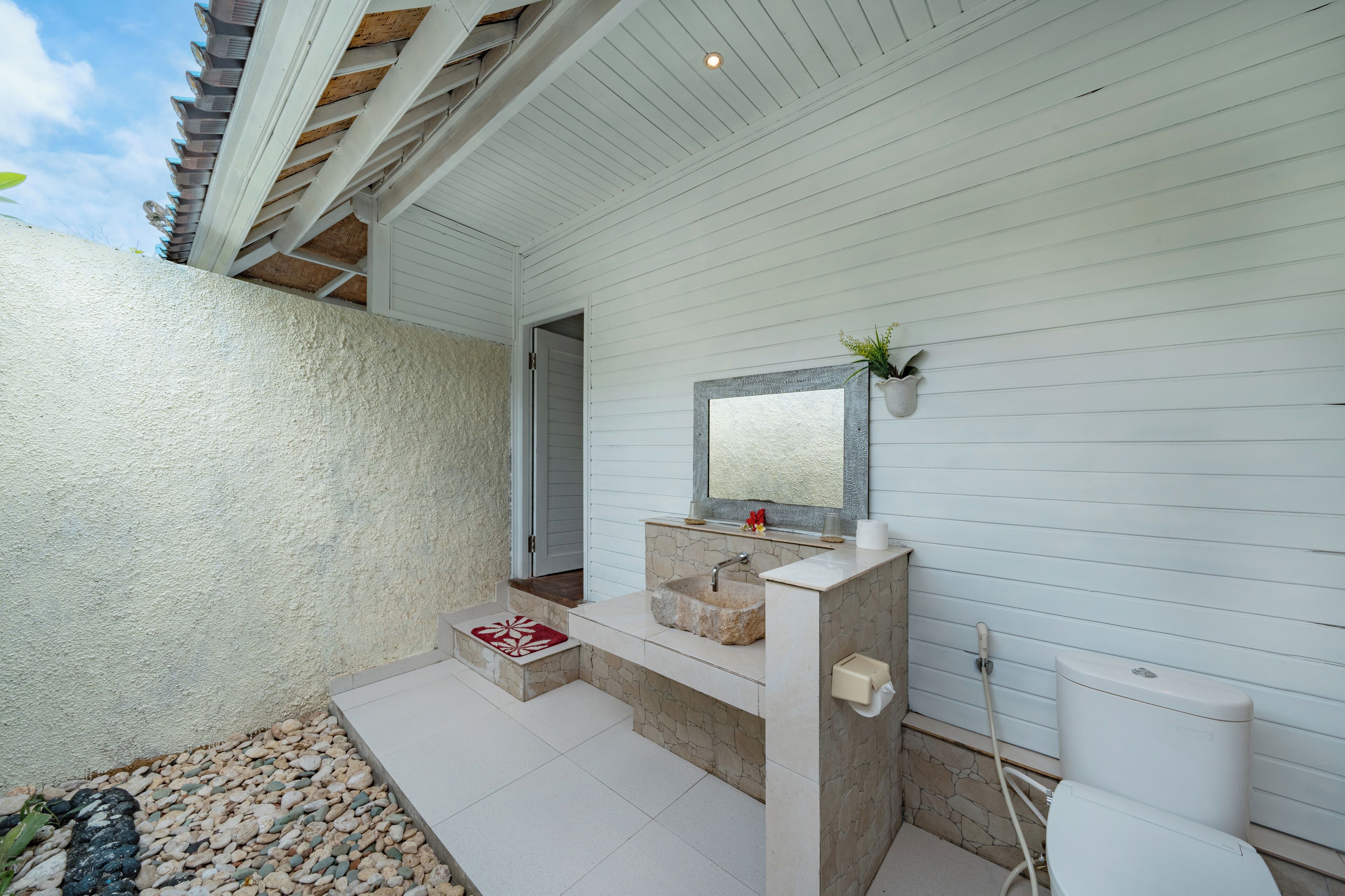 A bathroom with a stone sink, a mirror, and a toilet.