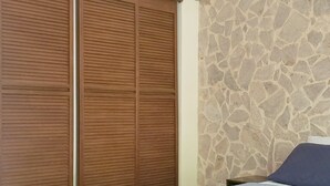 A bedroom with a bed, a ceiling fan, and a stone wall. - Casa Eco | Private Apartment In Taganga | 600 Meters away from beach (Taganga)