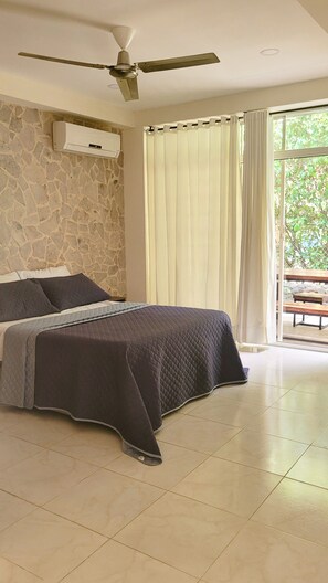 A bedroom with a bed, stone wall, ceiling fan, air conditioning unit, and a view of greenery outside. - Casa Eco | Private Apartment In Taganga | 600 Meters away from beach (Taganga)