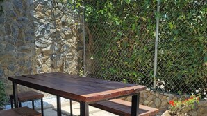 An outdoor patio with a stone wall, a wooden table with benches, and a potted plant. - Casa Eco | Private Apartment In Taganga | 600 Meters away from beach (Taganga)