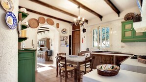 Una cocina rústica con vigas de madera, una mesa de comedor con sillas y un armario verde.