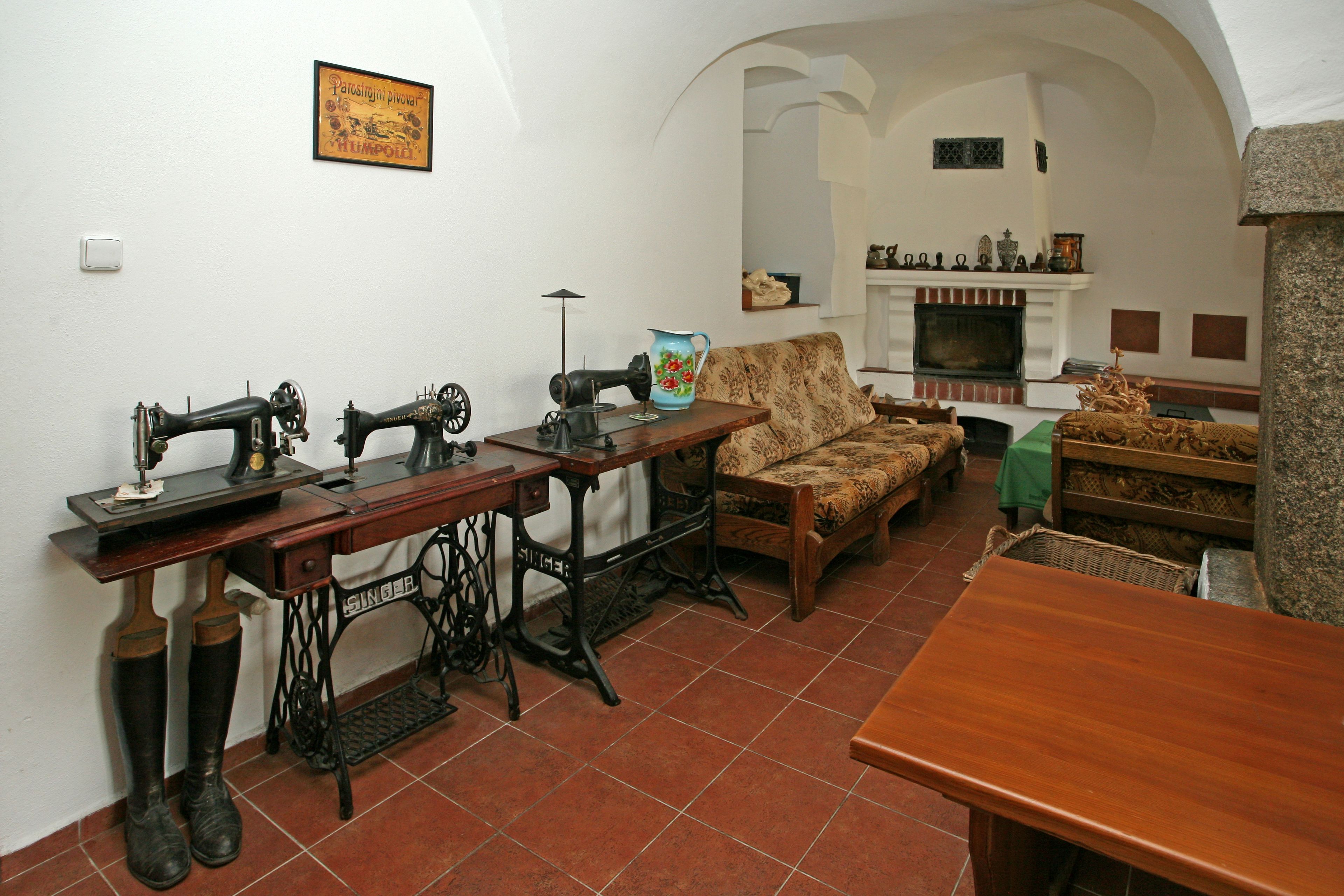A living room with a sewing machine, a patterned sofa, and a fireplace.
