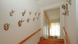 Una escalera con barandas de madera y un muro decorado con cráneos de animales.