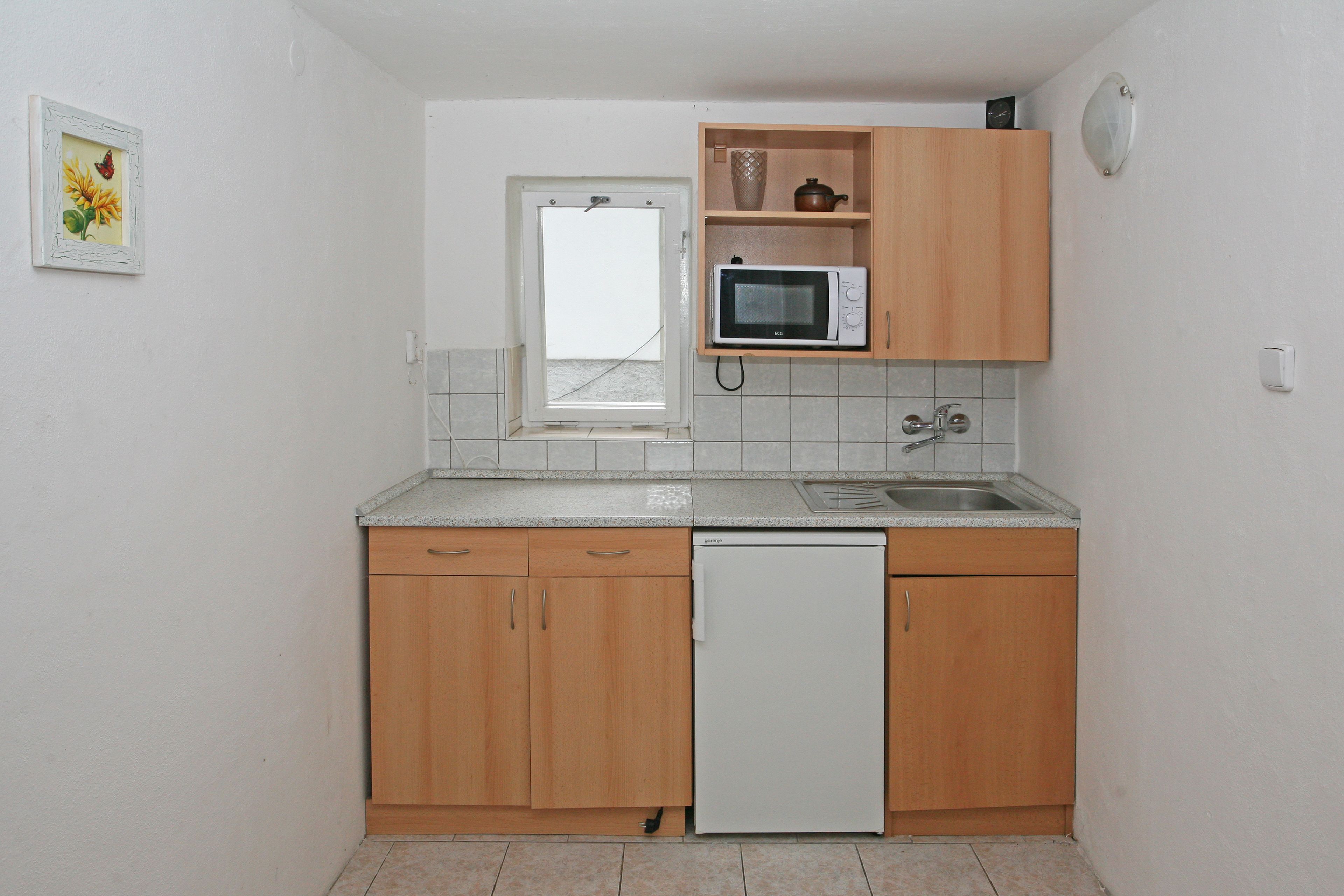 Een kleine keuken met houten kastjes, een magnetron en een vaatwasser.