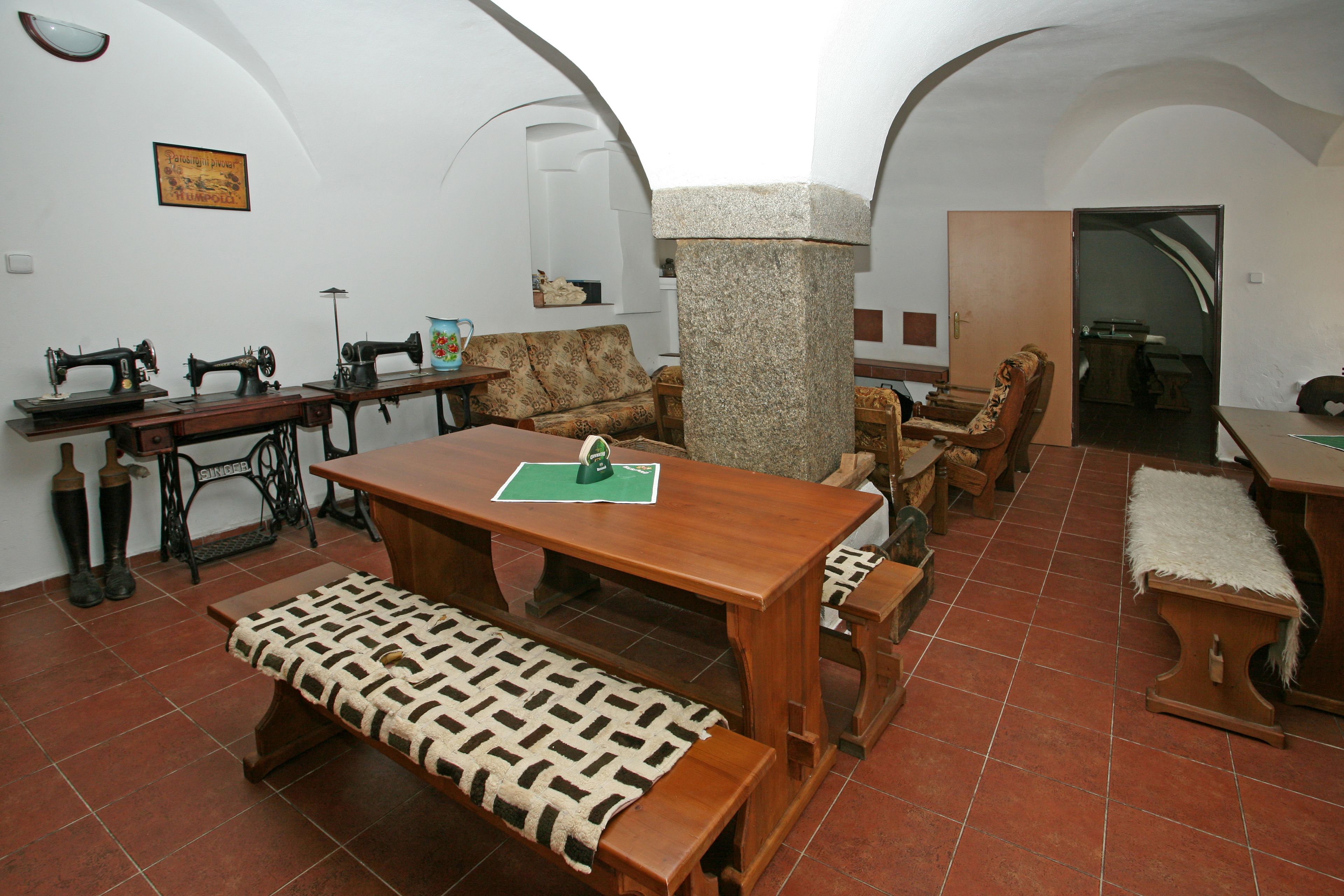 A room with a wooden table, a bench, and three vintage sewing machines.