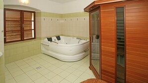 Un baño con una bañera grande, un armario de madera y una ventana con persianas.