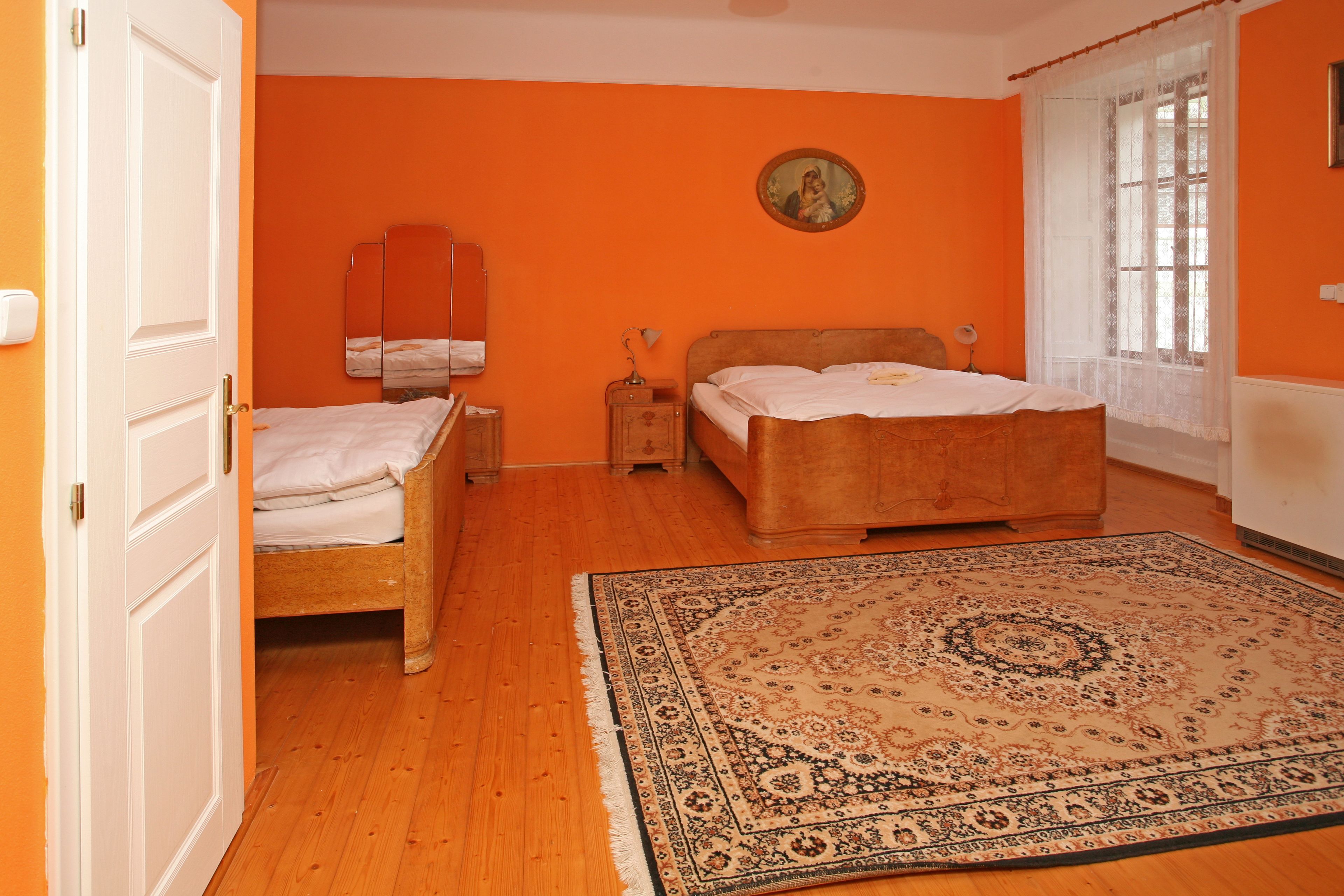 Un dormitorio con dos camas, un tapete grande, un espejo y una ventana con cortinas.