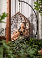 A wicker hanging chair in a garden setting.