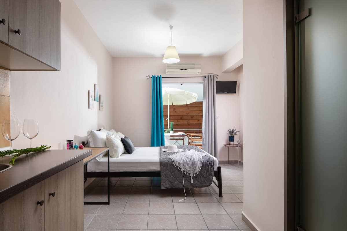 A compact bedroom with a bed, bedside table, and a view of the balcony.