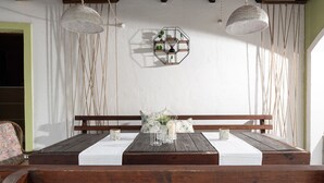 Une table à manger en bois, recouverte d’une nappe blanche, entourée de bancs en bois.