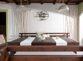 A wooden dining table with white tablecloth, surrounded by wooden benches.