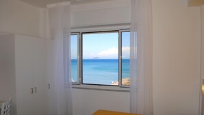 Una habitación con cama, ventana y vista al mar, además de un armario.