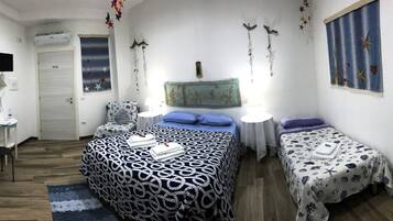 Ein Schlafzimmer mit einem großen Bett, zwei Einzelbetten, einem Schreibtisch und einem Stuhl.