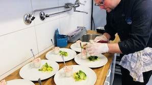 A chef preparing dishes with vegetables and seafood on a kitchen counter.