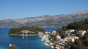 A coastal town with a marina, buildings with red roofs, and mountains in the background. - White Cloud Apartments (Korcula)