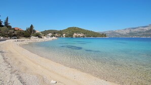A clear beach with a mountain in the background and a clear blue sky. - White Cloud Apartments (Korcula)