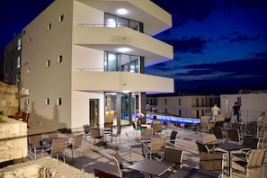 A modern building with a rooftop patio area featuring outdoor seating and a pool.
