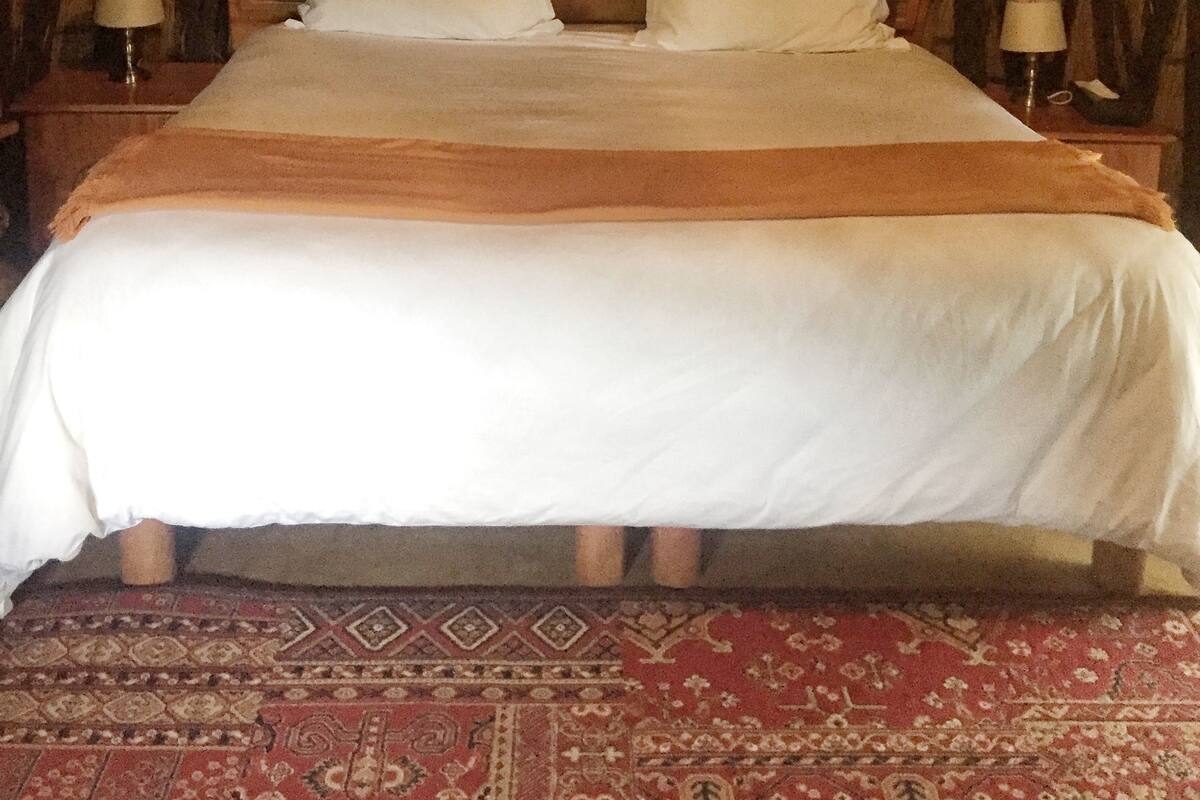 A bed with a wooden headboard, two bedside tables with lamps, and a hanging canopy.
