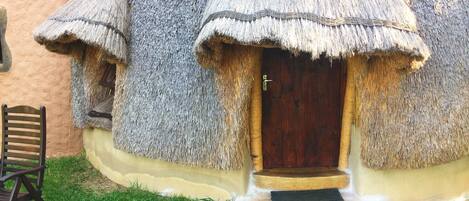 A traditional thatched-roof house with a wooden door and steps leading to the entrance.