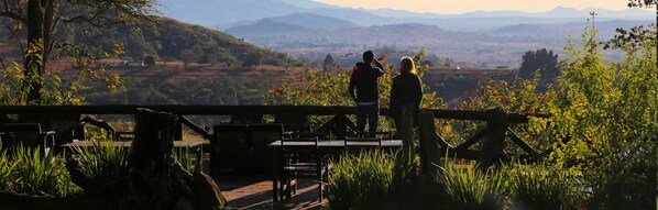 A scenic outdoor area with a wooden deck, tables, and chairs.