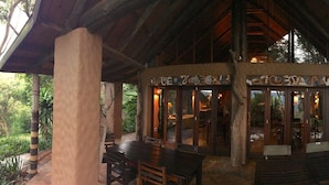 A wooden structure with a covered seating area and a sign with non-English script. - Phophonyane Falls Ecolodge (Piggs Peak)