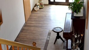 Een trap die leidt naar een kamer met een piano, een klein vloerkleed en decoratieve objecten.