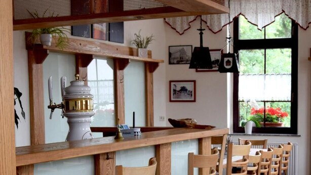 Een rij houten stoelen met beklede zittingen en rugleuningen, in een rij langs een houten toonbank geplaatst.