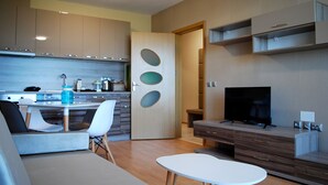 A modern kitchen with a dining area, a TV, and a sofa.