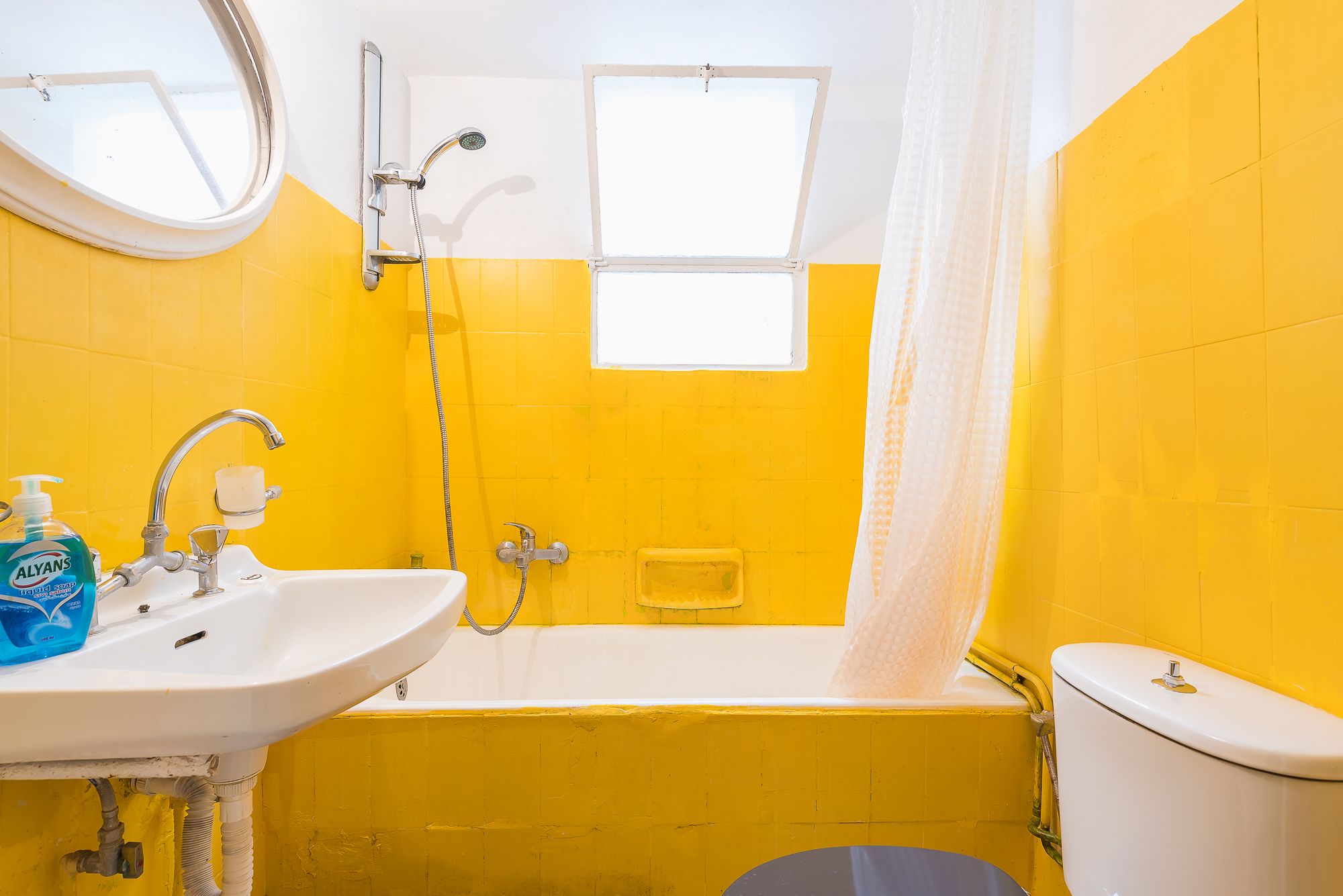 A bathroom with yellow walls, a white sink, a bathtub, and a toilet.