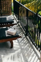 Ein Balkon mit schwarzem Metallgeländer, einer Holzbank und einer Pizzakiste.