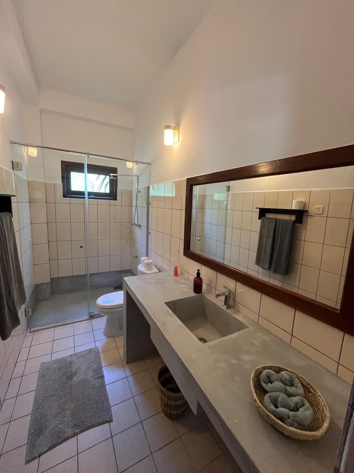 Un baño con ducha, inodoro, lavabo y un espejo grande.