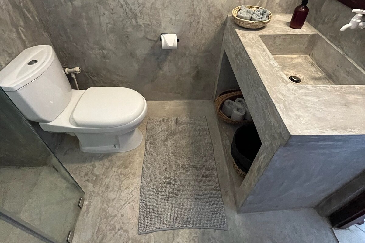 Une salle de bain comprenant des toilettes, un lavabo et un espace douche.
