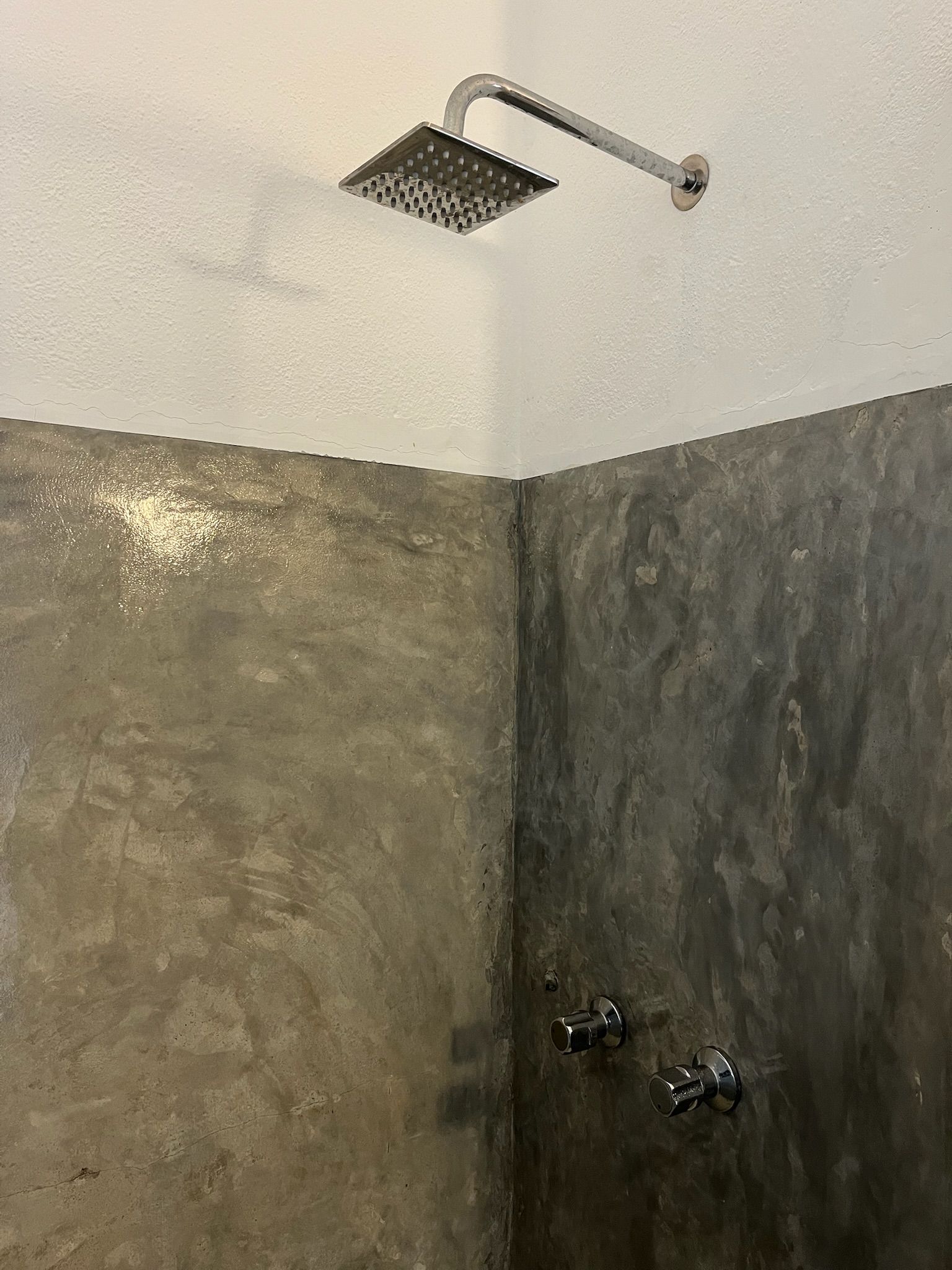 A shower with a handheld showerhead and two wall-mounted faucets.