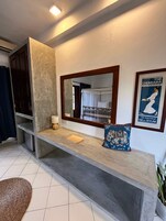 A bathroom with a large mirror, a towel rack, a sink, and a poster on the wall.