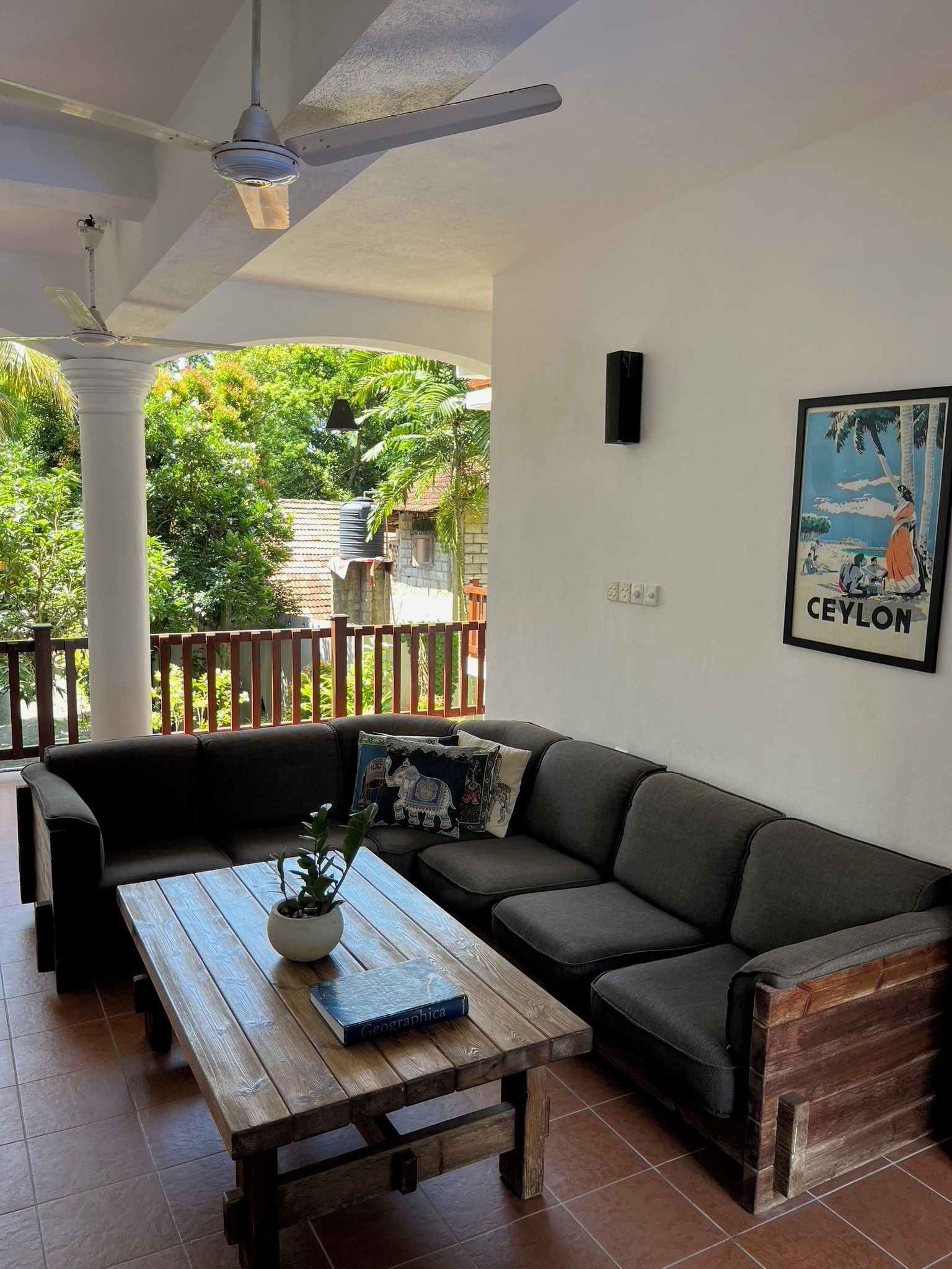 A living room with a sofa, a wooden table, and a ceiling fan.