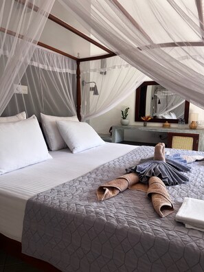 A bed with a canopy, pillows, a quilted bedspread, and towels. - Unawatuna Nor Lanka Hotel (Unawatuna)