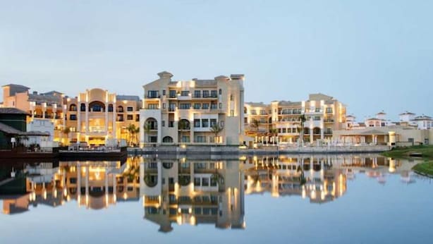 Ein Hotel am Wasser mit mehreren Gebäuden, die sich im ruhigen Wasser spiegeln.