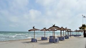 Ein Strand mit Sonnenschirmen und Liegestühlen.
